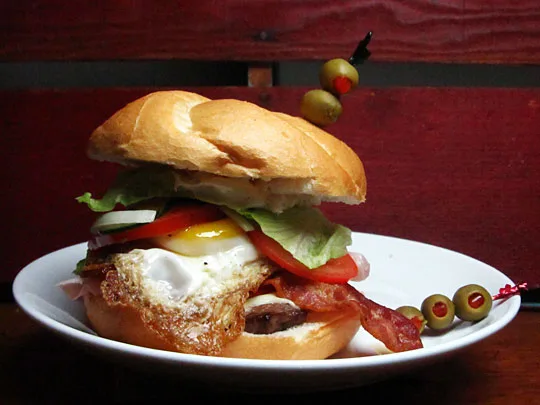 savvyhousekeeping el chivo uruguay sandwich steak, bacon, ham, mozzarella, tomatoes, mayonnaise, lettuce, red pepper, and a fried egg